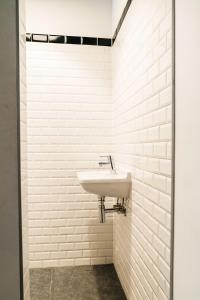 a bathroom with a sink and a white tile wall at Spui apartment in center in Amsterdam