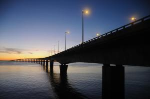 a bridge over the water with lights on at Hôtel Restaurant & Spa Plaisir in Le Bois-Plage-en-Ré