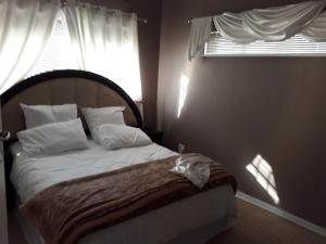 a bedroom with a bed with white pillows and a window at Robertsham (Halaal) Self Catering Cottages in Johannesburg