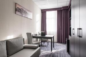 een hotelkamer met een tafel, een bank en een bureau bij Sky Business Hotel in Legnica