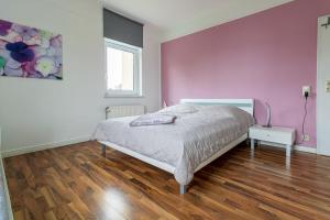 a bedroom with a bed and a pink wall at Haus-Godewind-Typ-3-1 in Binz