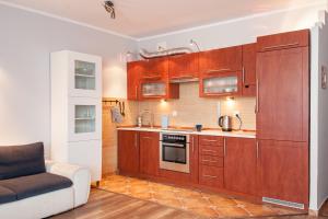 a kitchen with wooden cabinets and a couch at Fantastic By The Sea Apartment Set Up With Love in Gdańsk