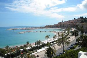 a view of a beach with palm trees and the ocean at app Le Rocazur avec piscine et parking en bord de mer à 500M du centre ville in Menton