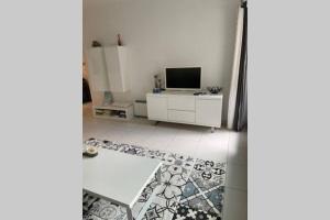 a living room with a television and a white cabinet at app Le Rocazur avec piscine et parking en bord de mer à 500M du centre ville in Menton