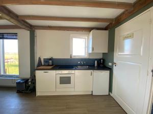 a kitchen with white cabinets and a sink and a window at Groepsverblijf "De Klosse" in Wanneperveen