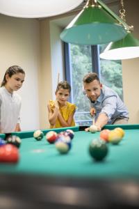 a family playing pool with a pool table at JUFA Hotel am Sigmundsberg in Mariazell