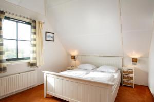een wit bed in een kamer met een raam bij Buitenplaats Villa 116 - Callantsoog in Callantsoog