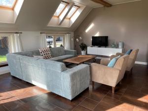 Una sala de estar con un sofá y sillas y un televisor. en De Boerderij - Buitenplaats Ruitenveen, privé, en Nieuwleusen