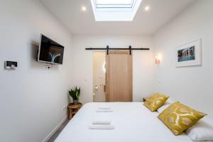 een witte slaapkamer met een bed en een televisie bij Beach Studio 35 in Zandvoort