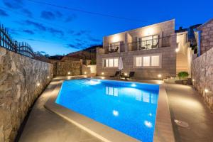 a swimming pool in front of a house at night at Apartments Villa Kabalero in Gruda