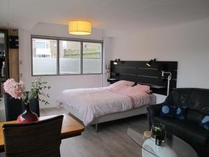 a bedroom with a bed and a couch and a table at Strandhuussie Texel in De Koog
