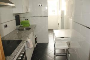 a white kitchen with a sink and a counter at Piso céntrico en Torrelavega in Torrelavega