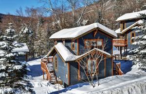 una cabaña de troncos en la nieve con nieve en Chalets Alpins - 14 Chemin Alpin, en Stoneham