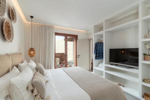 a white bedroom with a bed and a tv at Giorgio Deluxe Studio in Kattavía