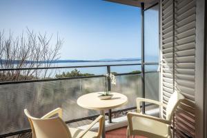 a balcony with a table and chairs and a view of the ocean at Hotel Zagreb in Crikvenica
