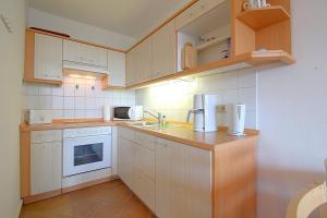 eine Küche mit weißen Geräten und Holzschränken in der Unterkunft Apartment 255 in Hohegeiß