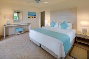 a bedroom with a large bed and a blue chair at Beach View Hotel in Saint James