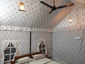 a room with a ceiling fan and two windows at Blue Coast beach resort in Alibaug