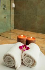 two candles with towels and a flower on a sink at Hotel Mumbai House Airoli, Navi Mumbai in Navi Mumbai