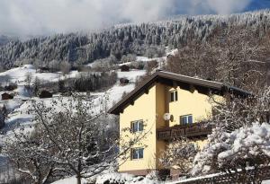 una casa amarilla con nieve en el techo en Ferienwohnung Hildegard, en Silbertal
