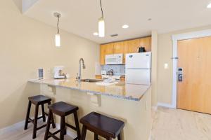 a kitchen with a counter with stools and a refrigerator at Elation 5605 Bliss by the Bay in Destin