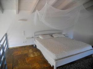 a bedroom with a white bed with a canopy at Natur-Steinhaus mit Meerblick: hell, ruhig, exklusiv, strandnah in Liapades