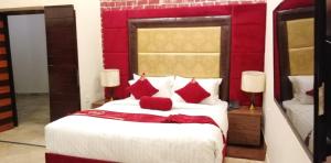Hotel The Holiday في لاهور: غرفة نوم مع سرير أبيض كبير مع وسائد حمراء