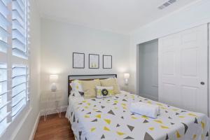 a white bedroom with a large bed with yellow triangles at @ Marbella Lane - Buckingham Place Laundry + P in Pacifica
