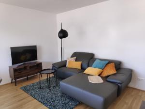 a living room with a blue couch and a tv at City Appartement Wien-Schwechat in Schwechat