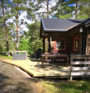 Cabaña de madera con mesa y sillas en una terraza en Tofvehults Boende, en Skaftet