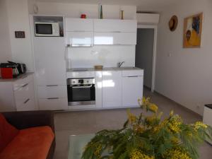 テウル・シュル・メールにあるPlage de Miramarの白いキャビネットとテーブル付きのキッチンが備わります。