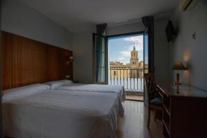 Habitación de hotel con 2 camas y ventana grande. en Hotel Hispania en Zaragoza