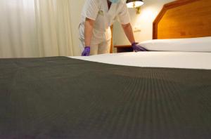 un homme fait un lit dans une chambre d'hôtel dans l'établissement Hotel Hispania, à Saragosse