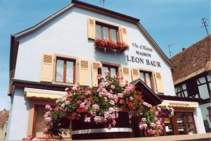 un edificio blanco con flores delante en Le Victoria à Eguisheim, 4-6 p, 3étoiles en Eguisheim
