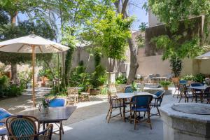 an outdoor patio with tables and chairs and an umbrella at Can Bordoy Grand House & Garden in Palma de Mallorca