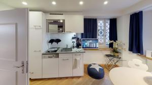 a kitchen with white cabinets and a sink and a table at Signature Bijou in Zürich