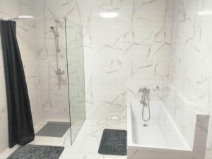 a white bathroom with a shower and a sink at Biały Dom in Piecki