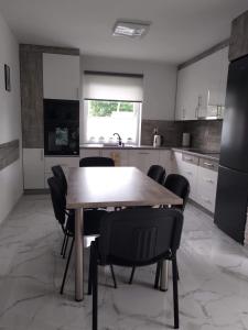 a kitchen with a wooden table and black chairs at Biały Dom in Piecki