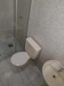 a bathroom with a toilet and a sink at Cond Apartamentos Chalés San Marino in Ubatuba