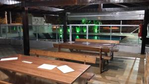 ein Restaurant mit Bänken und einem Pool im Hintergrund in der Unterkunft Cond Apartamentos Chalés San Marino in Ubatuba