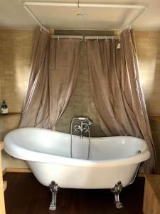 a bath tub in a bathroom with a curtain at Spa Les Jardins De Chiron Lodges et Tiny House dans le sud in Sauve
