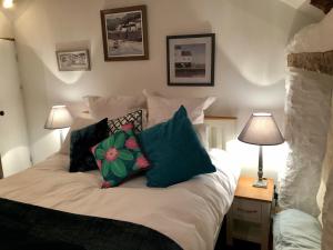 a bed with pillows on it in a bedroom at Sixpence Cottage in Penryn