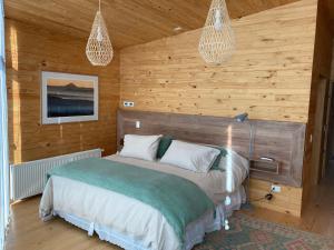1 dormitorio con 1 cama en una pared de madera en Casas Punta Costanera en Pichilemu
