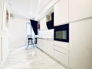 a white kitchen with white cabinets and a tv at Studio Six in Umag
