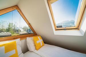 ein kleines Schlafzimmer mit einem Fenster und einem Bett mit gelben Kissen in der Unterkunft Tamok Lifestyle Villa in Zakopane