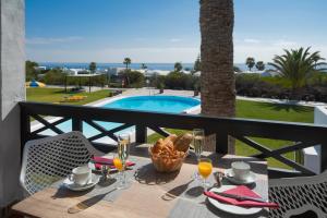 a table with food and drinks on a balcony with a pool at Charco del Palo apartments en complejo nudista FKK nudist resort Castillo de Papagayo in Charco del Palo