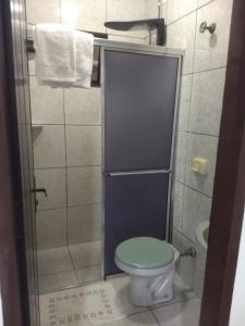 a bathroom with a toilet with a glass door at Pousada Nativos in Miranda
