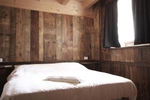 uma cama num quarto com paredes de madeira e uma janela em Tabià Alleghe vista lago, monte Civetta Dolomiti em Alleghe