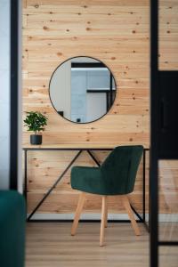 Green Loft Apartament في بيالا بودلاسكا: كرسي أخضر للجلوس بجانب مكتب مع مرآة