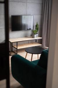 uma sala de estar com uma televisão e uma mesa em Green Loft Apartament em Biała Podlaska